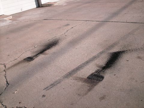 1970 Ford Mustang - Tire marks and oil stains are visible on cracked asphalt, suggesting recent vehicle activity.