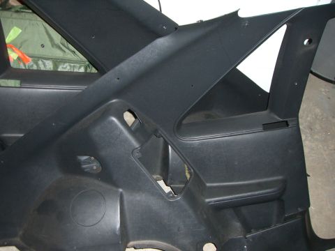 1988 Ford Bronco - This black interior trim panel features cutouts for components and a circular speaker grille, likely from an older vehicle.