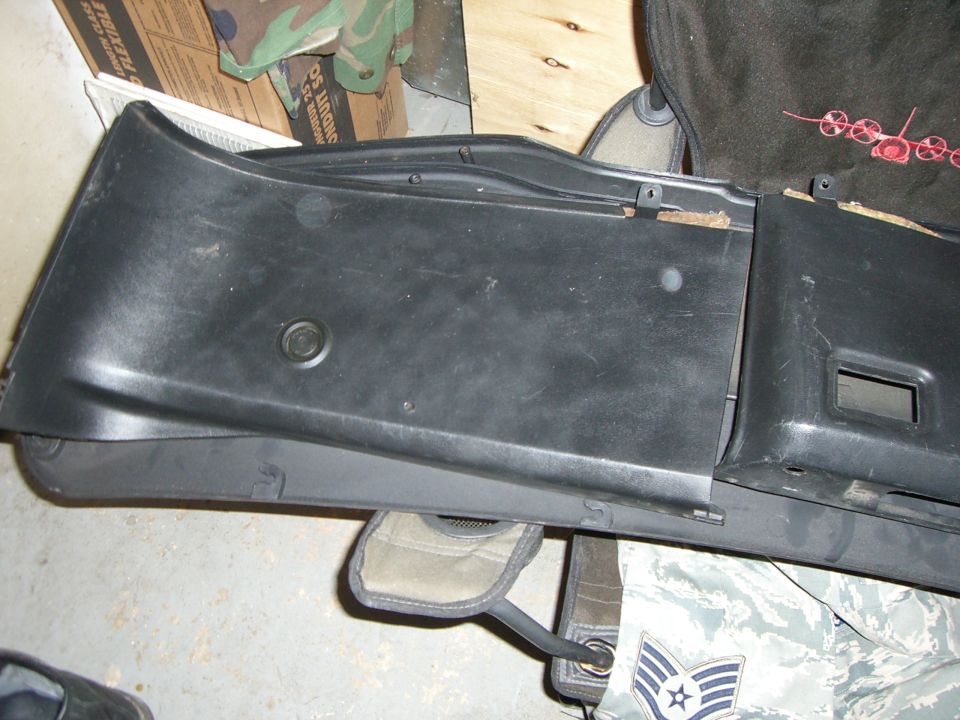 black plastic dashboard trim piece with a circular cutout and a rectangular cutout