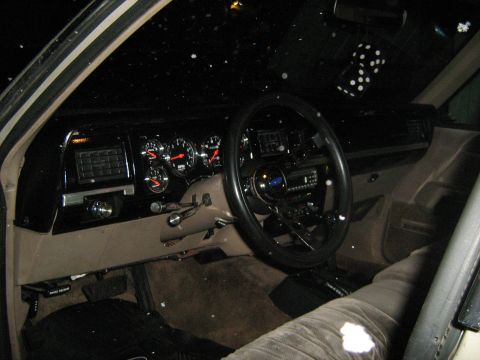 1988 Mercury Grand Marquis - The interior of a 1988 Mercury Grand Marquis features aftermarket gauges and a pair of fuzzy dice hanging from the rearview mirror.