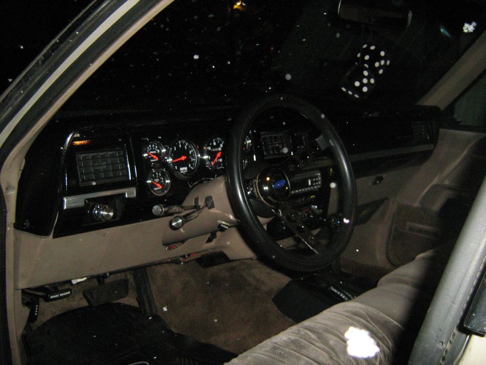 1988 Mercury Grand Marquis interior with aftermarket gauges and dice hanging from mirror