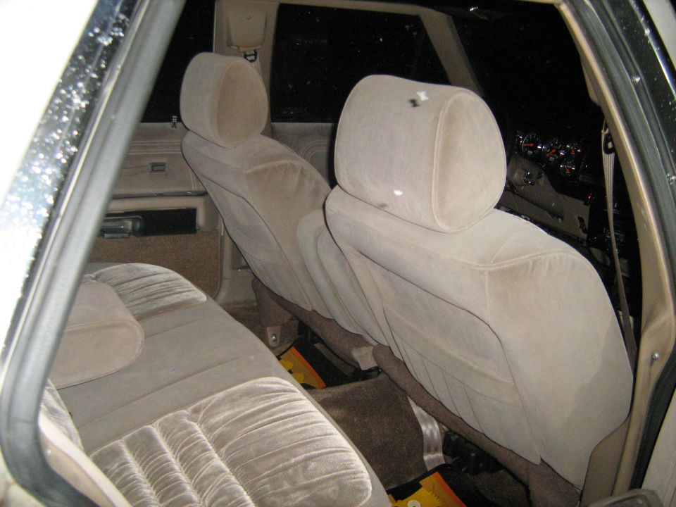 Interior of a car with tan velour seats. The rear seat and front seatbacks are visible