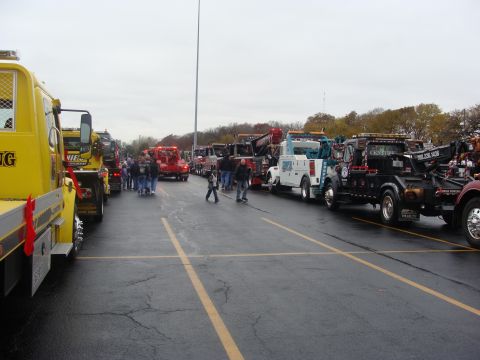 1992 Ford Bronco - A collection of tow trucks are lined up in a parking lot on an overcast day.