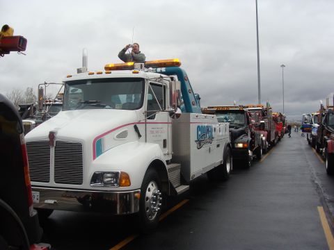 1992 Ford Bronco - Several tow trucks are parked in a line on a cloudy day.