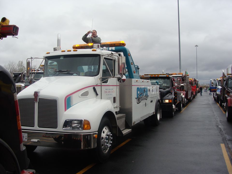 Line of tow trucks, one white Kenworth in foreground