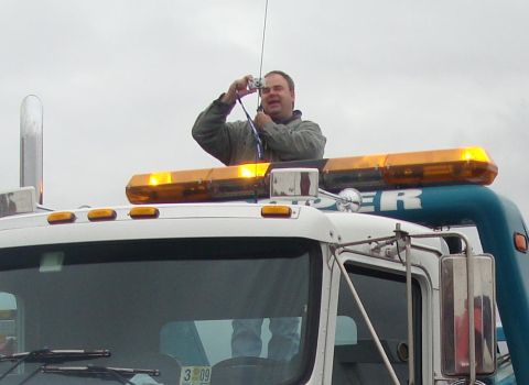 1992 Ford Bronco - A man stands atop a tow truck, holding a camera to take a picture.