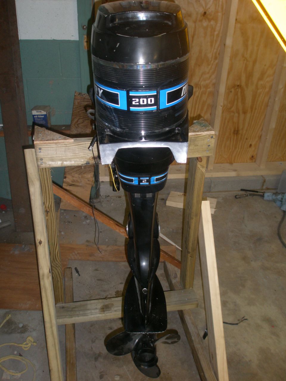 Black outboard motor with blue stripe and '200' label, mounted on a wooden stand