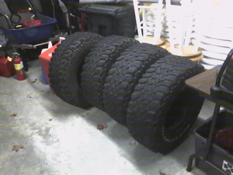 1996 Ford Bronco - Four off-road tires are stacked on a garage floor.