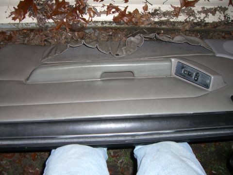 1988 Ford Bronco - Interior door panel with torn fabric and window controls, showing signs of wear.