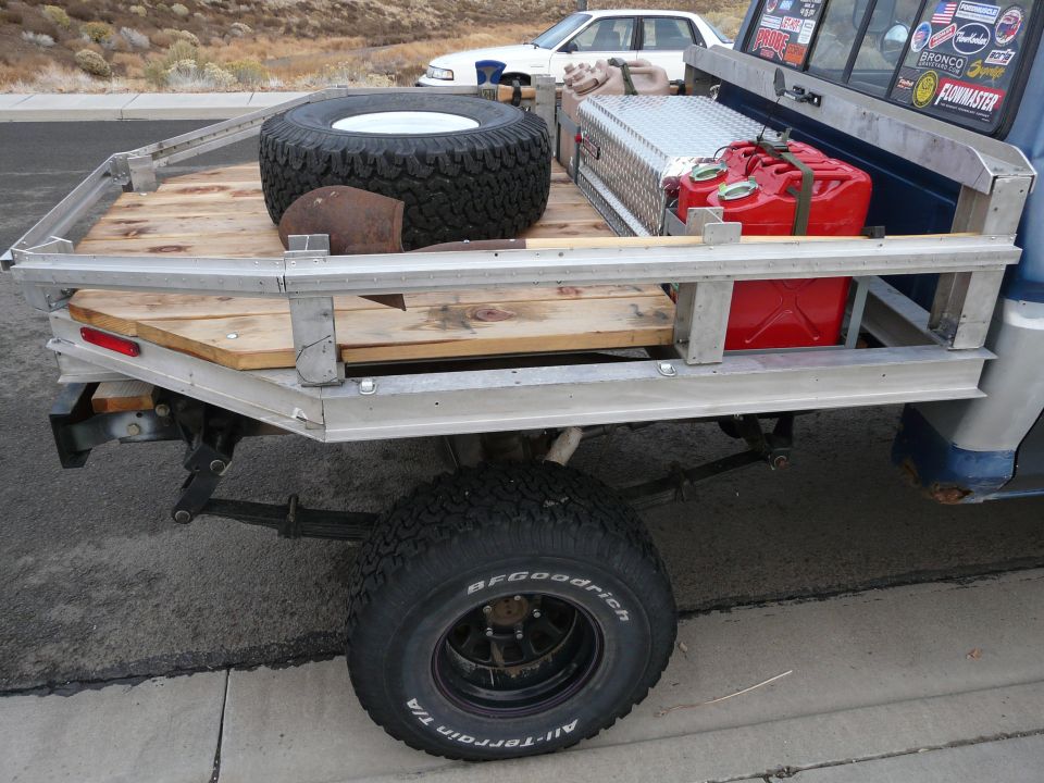Aluminum utility trailer with spare tire, toolbox and red fuel can on wood bed