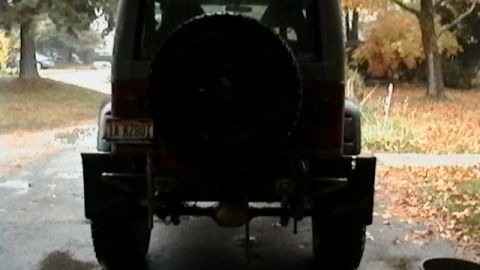 1989 Jeep YJ - The rear of a Jeep YJ is shown with a spare tire and aftermarket bumper.