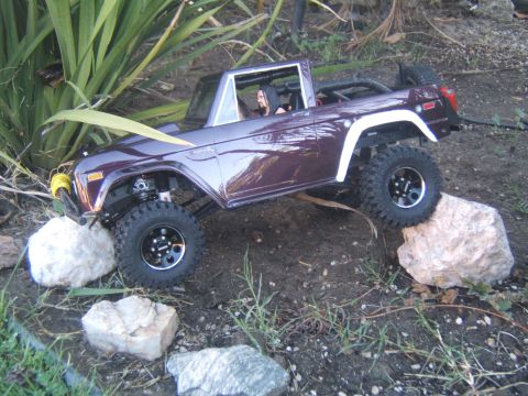 1988 Ford Bronco - A remote-controlled crawler truck navigates a path through rocks and foliage.