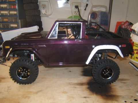 1988 Ford Bronco - Side view of a purple RC crawler, resembling a 1978 Ford Bronco, with a driver figure inside.