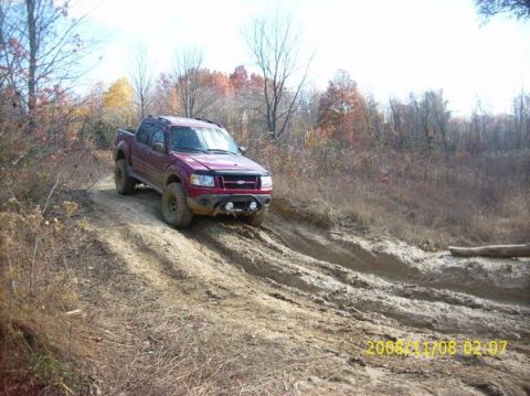 2002 Ford Sport Trac - A red 2002 Ford Sport Trac navigates a muddy off-road trail during autumn.