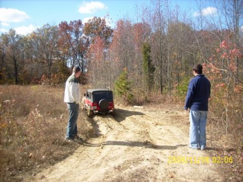 2002 Ford Sport Trac - Jeep Wrangler navigating a rough dirt path in a wooded area during autumn.