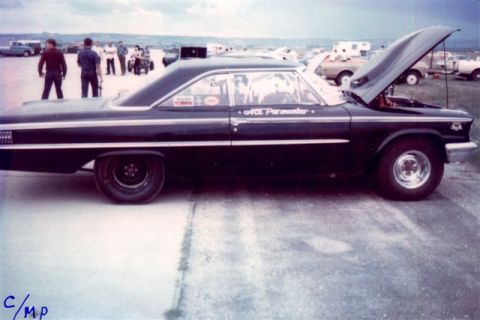 1963 Ford Galaxie - A black 1964 Ford Galaxie drag car is parked at a race track with people in the background and the hood up.