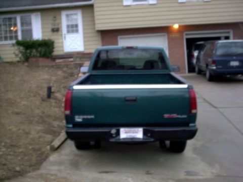 1995 GMC Sierra 1500 - Rear view of a green 1995 GMC Sierra 1500 pickup truck parked in a driveway, with a house and garage in the background.