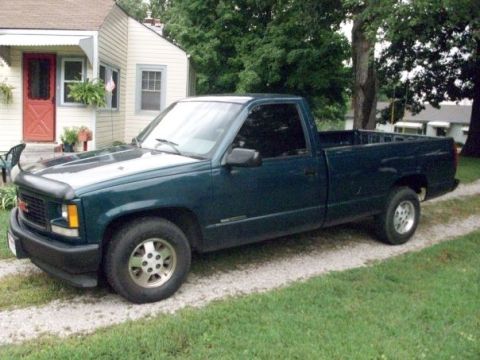 1995 GMC Sierra 1500 - This 1995 GMC Sierra 1500 pickup truck is seen from a three-quarter front angle, parked on a gravel driveway next to a house.