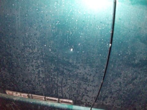 1995 GMC Sierra 1500 - Close-up of a teal truck door with water droplets and a chrome emblem.