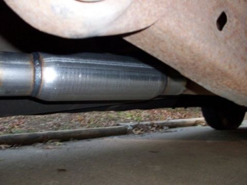 1995 GMC Sierra 1500 - Close-up view of an exhaust pipe and rusty frame components, with visible weld marks.