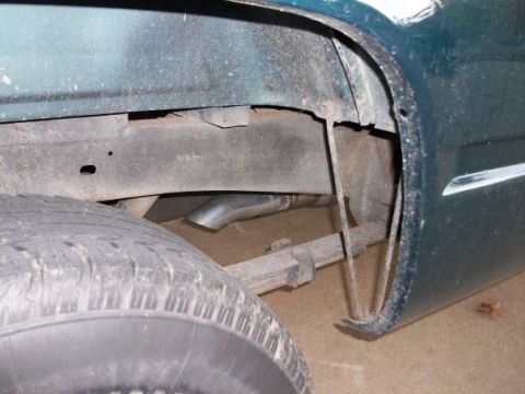 1995 GMC Sierra 1500 - Close-up of the rear wheel well area on a 1995 GMC Sierra 1500, showing the exhaust pipe and leaf spring.