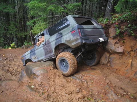 1989 Ford Bronco - Ford Bronco tackling a challenging off-road course, with mud and rocks on the trail.