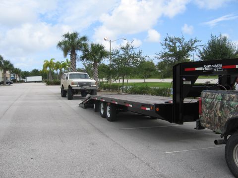1989 Ford Bronco - A lifted 1989 Ford Bronco is parked next to a flatbed trailer.