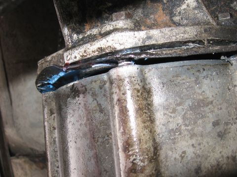 1989 Ford Bronco - Transmission gasket leak showing blue sealant squeezed out from the seal.