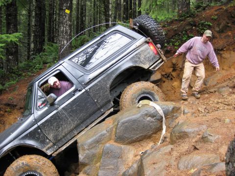 1979 Ford Bronco - A black SUV is shown struggling on a steep, rocky incline during an off-road excursion.