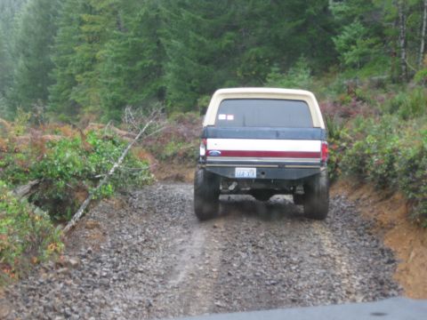 1979 Ford Bronco - Ford Bronco driving on a rough gravel road through a wooded area.
