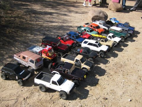 1988 Ford Bronco - A variety of remote-controlled trucks and SUVs are displayed outdoors on a sunny day.