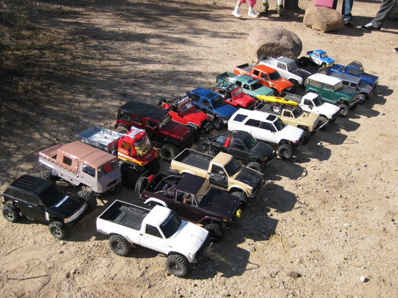 Collection of RC trucks and SUVs lined up on dirt ground