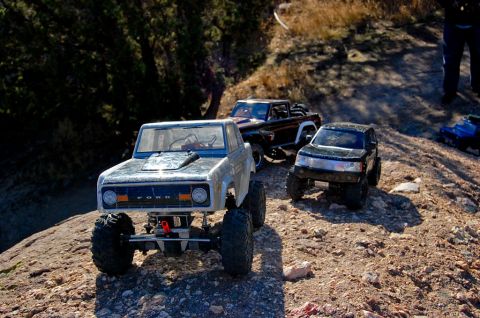 1988 Ford Bronco - A collection of remote control off-road vehicles, including a 1988 Ford Bronco, navigate a rocky trail.