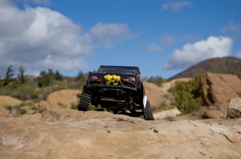 1988 Ford Bronco - A remote-controlled rock crawler navigates a , rocky landscape under a partly cloudy sky.