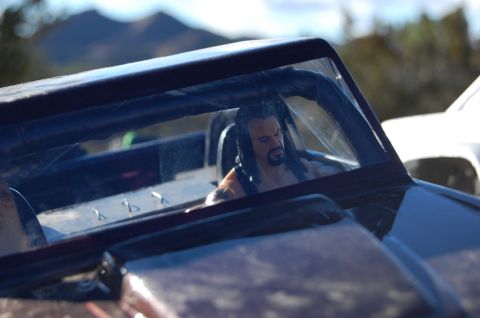 1988 Ford Bronco - A toy figure resembling The Undertaker sits behind the wheel of a toy vehicle, with mountains in the background.