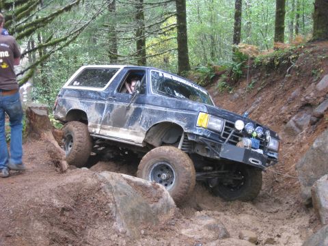 1979 Ford Bronco - This modified SUV is tackling a challenging off-road course with steep inclines and rough terrain.