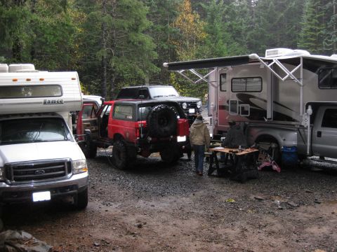 1979 Ford Bronco - Multiple vehicles, including campers and off-road SUVs, are parked together in a wooded campsite.
