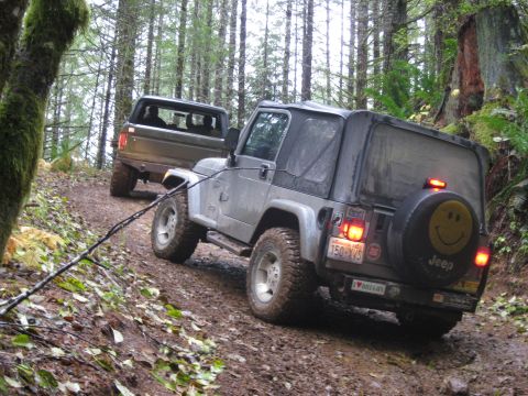 1979 Ford Bronco - Two off-road vehicles navigate a muddy forest trail, with a Jeep in the foreground and a Ford Bronco following behind it appears to be foll…