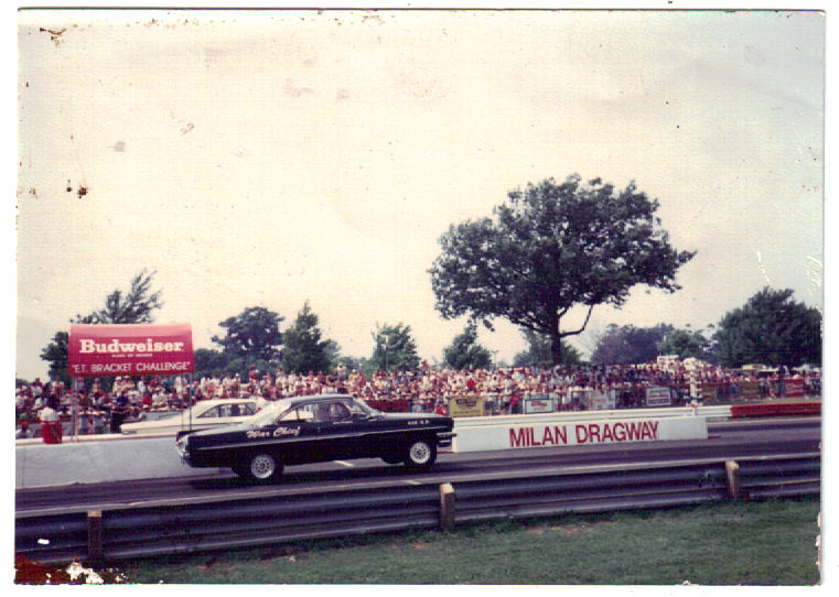 Black "War Chief" 1960s drag car racing a white car at Milan Dragway, vintage photo