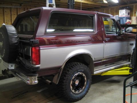1996 Ford Bronco - This two-tone Ford Bronco is shown from the rear three-quarter view, elevated in a workshop setting.