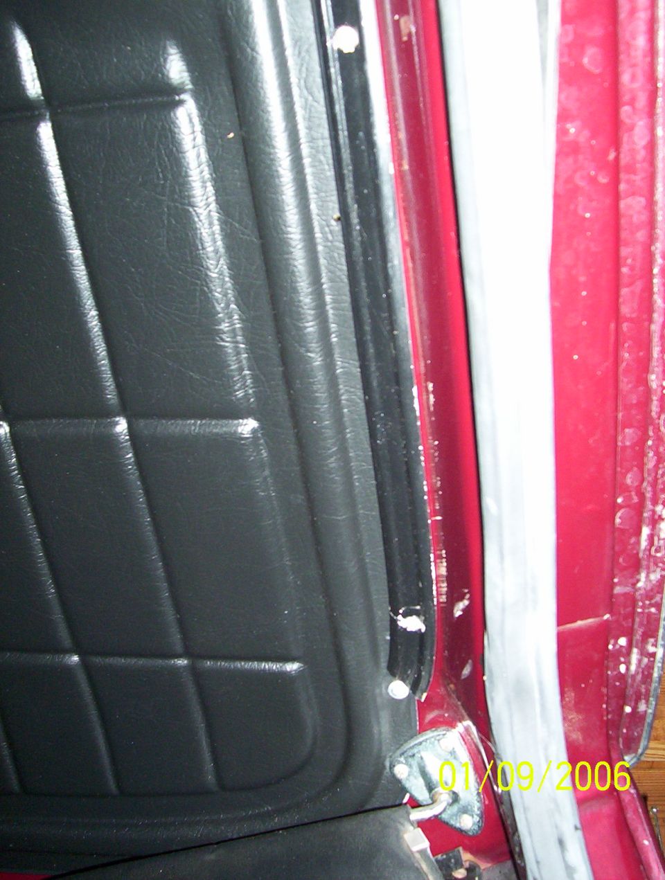 Door jamb with black vinyl panel, red pillar, weatherstrip and metal striker plate