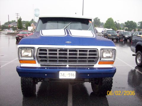 1978 Ford Bronco - A blue Ford F-Series truck is parked in a lot on a rainy day. Other vehicles are visible in the background.