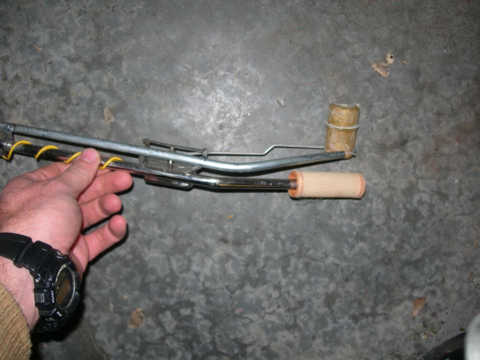 Hand holding a metal fuel sending unit with yellow wire wrapping and a float mechanism
