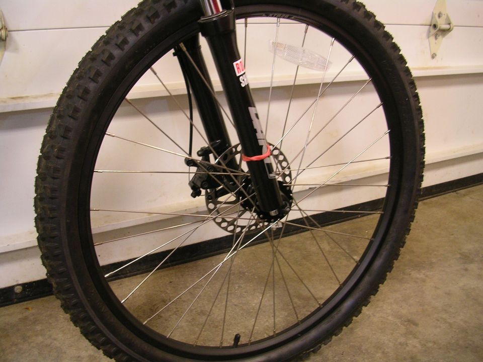 Bicycle front wheel with knobby tire, spokes, and RockShox suspension fork with disc brake