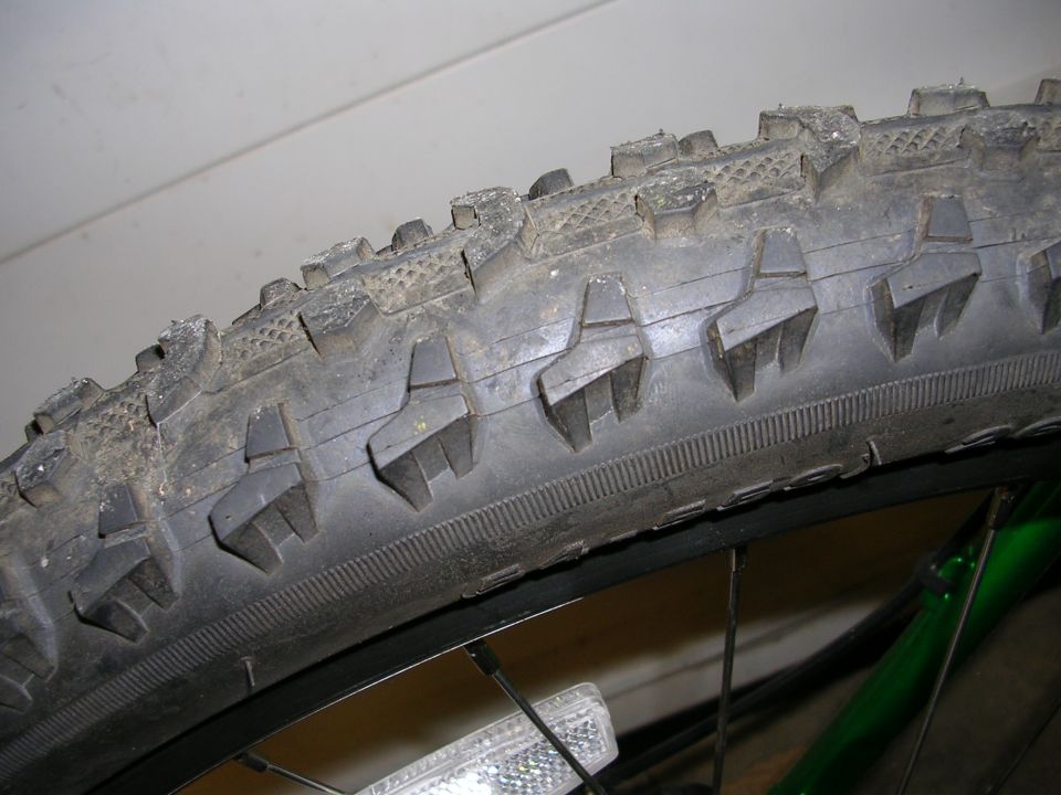 Close-up of knobby bicycle tire tread with dirt on it
