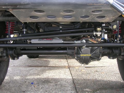 1996 Ford Bronco - Close-up of the steering system and differential cover on a vehicle's undercarriage.