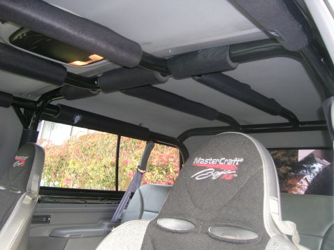 1996 Ford Bronco - The interior of a vehicle shows a roll cage with padded bars and MasterCraft Baja seats.