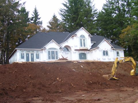 1991 Ford Bronco - An excavator works on a construction site where a house is covered in Tyvek wrap.