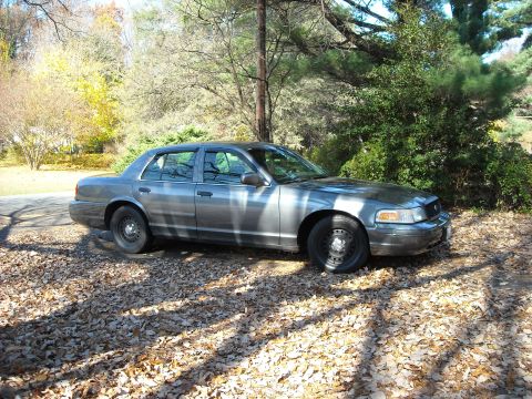 2000 Ford Crown Victoria - This 2000 Ford Crown Victoria sedan is seen from a three-quarter front angle, parked outdoors on a driveway covered in fallen leaves.
