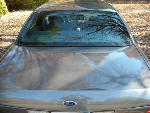 2000 Ford Crown Victoria - The rear of a 2000 Ford Crown Victoria, showing its grey paint and the reflection of trees in the rear window.